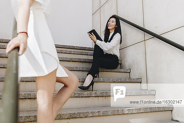 Geschäftsfrau steht neben einem lächelnden Mitarbeiter auf einer Treppe