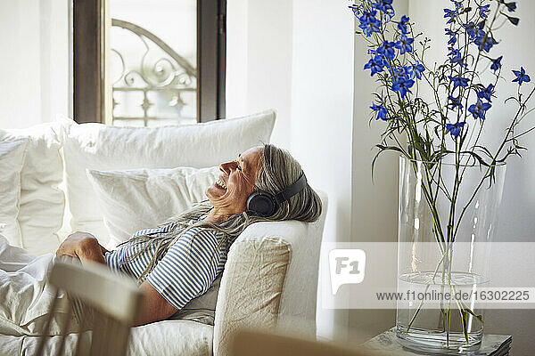 Smiling woman with closed eyes enjoying music in living room