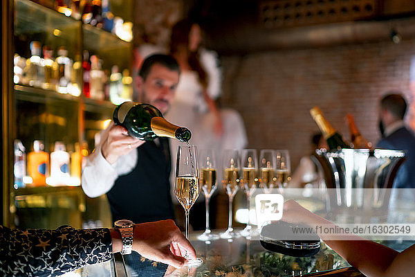 Barkeeper serviert einem Mann und einer Frau an der Theke in einer Kneipe ein Getränk