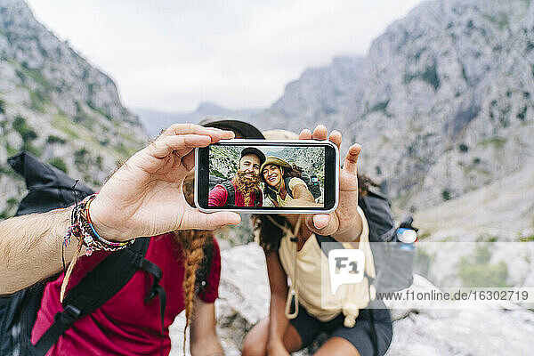 Paar  das ein Selfie mit dem Handy macht  während es auf einem Felsen an der Ruta Del Cares sitzt  Asturien  Spanien