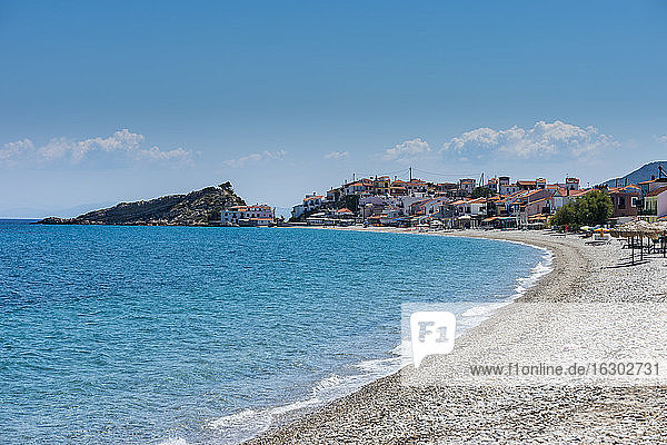 Griechenland  Nord-Ägäis  Kokkari  Felsiger Küstenstrand im Sommer mit Dorf im Hintergrund