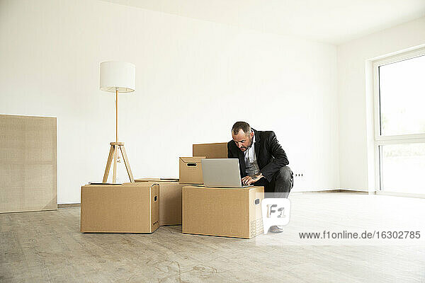 Businessman using laptop on cardboard box while working from new home