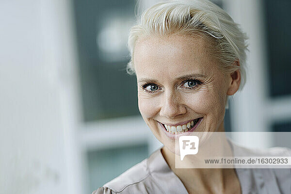 Close-up of cheerful businesswoman with short blond hair in office
