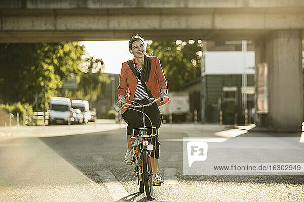 Glückliche junge Frau fährt Fahrrad auf der Straße in der Stadt