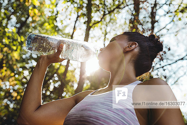 Frau trinkt in der Sonne Wasser aus einer Plastikflasche