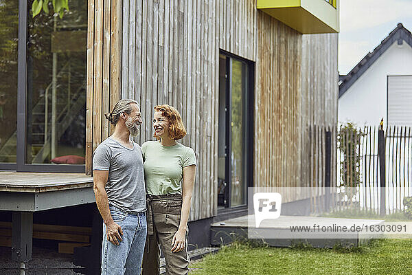Romantic couple looking at each other while standing outside tiny house in yard