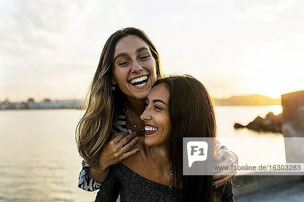 Smiling young woman piggybacking friend at promenade