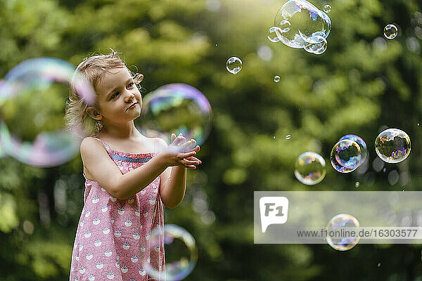 Nettes Mädchen schaut auf Blasen im Park