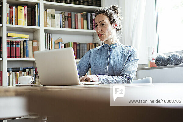Selbstbewusste Geschäftsfrau  die einen Laptop auf dem Tisch benutzt  während sie in einem Cafe sitzt