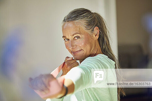 Lächelnde Frau  die mit einem Widerstandsband zu Hause trainiert