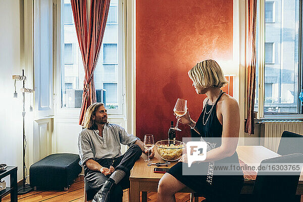 Young male and female friends drinking wine during party at home