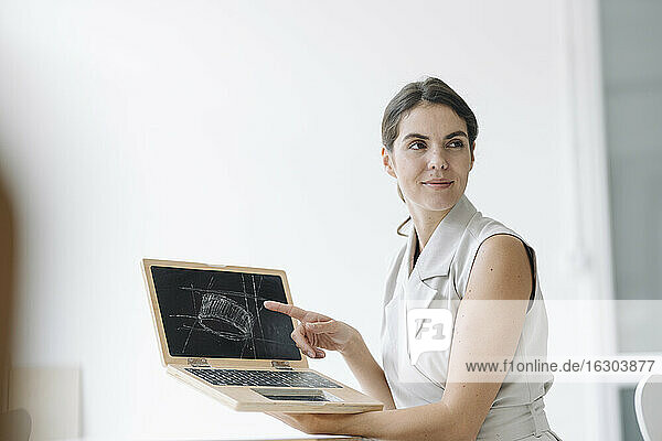 Lächelnde Geschäftsfrau zeigt Infografik auf Laptop im Büro