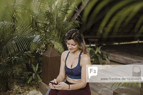 Lächelnde Frau mit Smartphone in einer Hütte