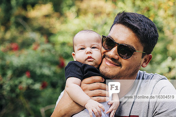 Loving man carrying cute son at park during weekend