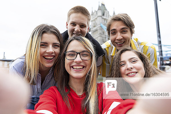 Fröhliche männliche und weibliche Freunde nehmen Selfie in der Stadt