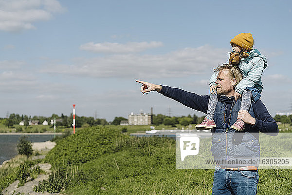 Vater zeigt auf den Rhein und nimmt seine Tochter auf die Schulter