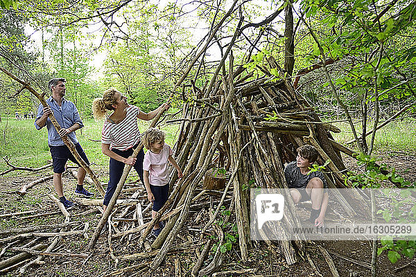 Familie baut Lager mit Baumstamm im Wald