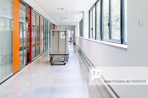 Robotic trolley with metallic container moving in hospital corridor