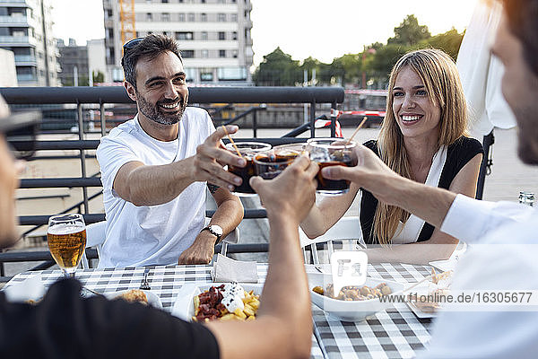 Glückliche Freunde stoßen in einem Straßencafé mit spanischem Wermut an