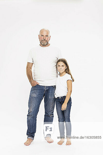 Bald father with daughter standing against white background