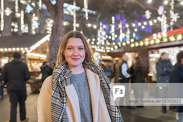 Schöne Frau auf dem beleuchteten Weihnachtsmarkt bei Nacht