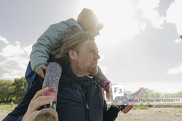 Vater trägt Tochter auf der Schulter an einem sonnigen Tag