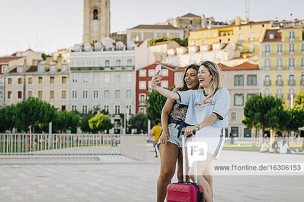 Fröhlicher Tourist  der ein Selfie mit seiner Freundin macht  während er auf einem Fußweg in der Stadt steht