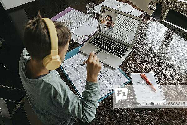 Schoolboy learning at home  using laptop and headphones