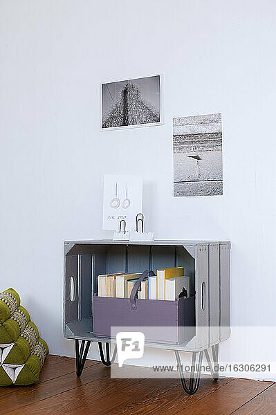 Photographs hanging over DIY bookshelf made of wooden crate
