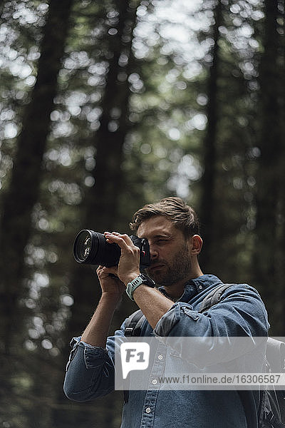 Nahaufnahme eines männlichen Wanderers  der im Wald stehend mit der Kamera fotografiert