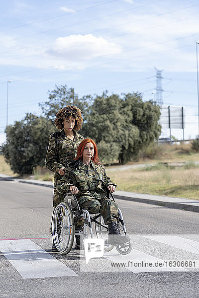 Ein Soldat hilft einem behinderten Militärangehörigen im Rollstuhl  während er auf der Straße steht