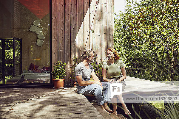 Romantisches Paar  das sich gegenseitig ansieht  während es vor dem Haus sitzt