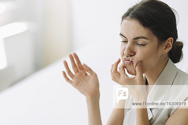 Playful woman making faces while sitting at office