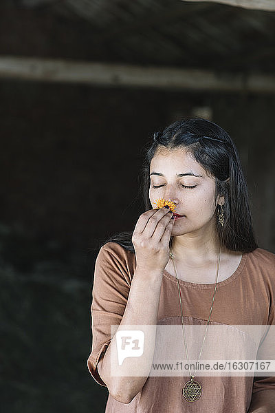 Beautiful woman smelling fresh orange flower