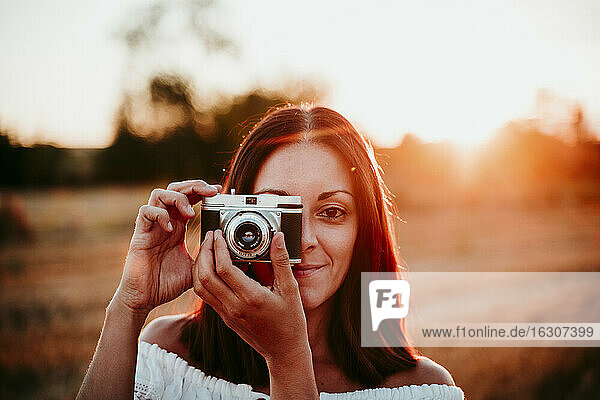 Frau mit alter Kamera bei Sonnenuntergang