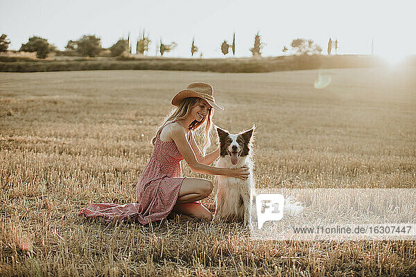 Woman enjoying with border collie dog in wheat field during sunset