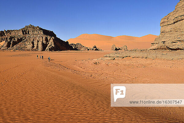 Algeria  Sahara  Tassili N'Ajjer National Park  People hiking between rocks and dunes of Tin Merzouga