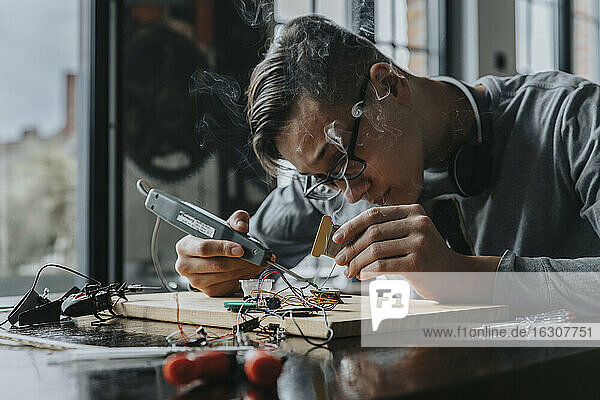 Young man tinkering with soldering iron at home