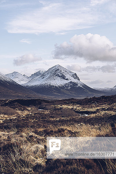 UK  Scotland  Brown grassy landscape of Isle of Skye in winter with snowcapped mountains in background