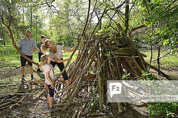 Mutter und Tochter bauen ein Lager auf  während Vater und Bruder im Hintergrund im Wald Holz sammeln