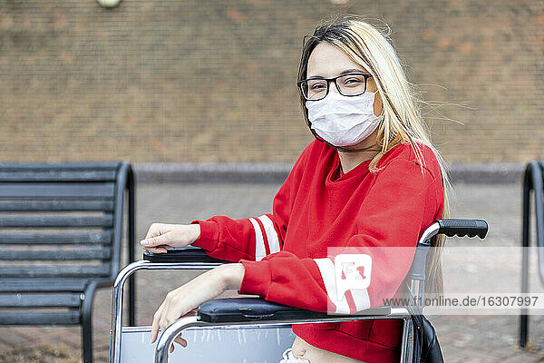 Behinderte Frau im Rollstuhl trägt Gesichtsmaske während des Ausbruchs des Coronavirus