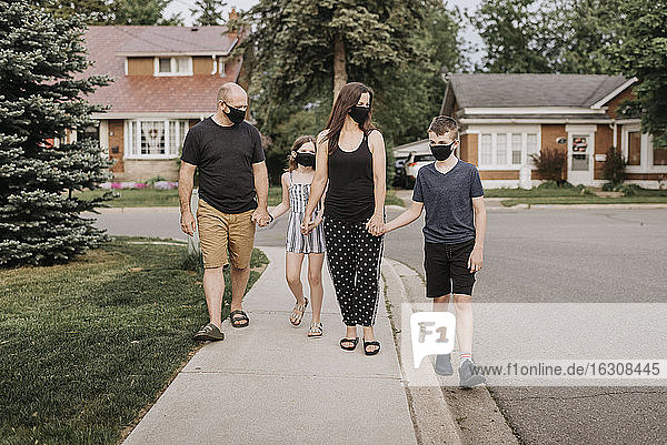 Familie mit Schutzmasken beim Spaziergang im Freien