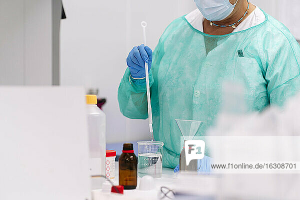 Nahaufnahme einer Wissenschaftlerin bei einem Experiment auf einem Tisch im Labor