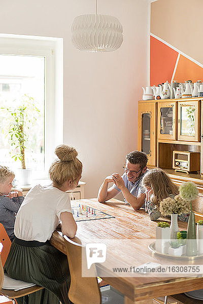 Family playing board game on dining table at home during weekend