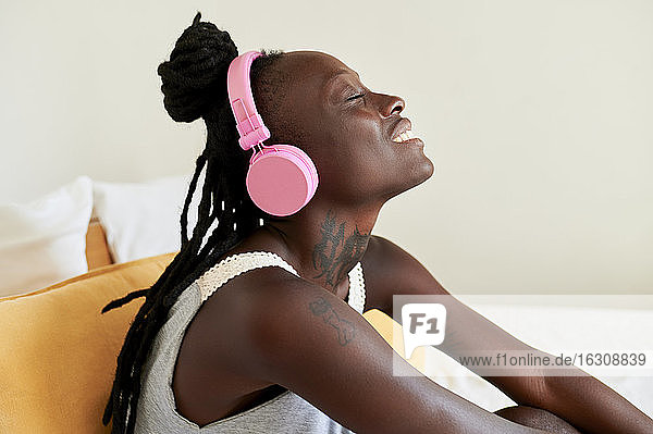 Schöne Frau hört Musik,  während sie zu Hause auf dem Bett sitzt