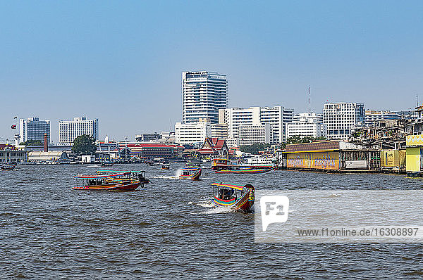 Thailand  Bangkok  Fähren auf dem Fluss Chao Phraya mit der Skyline der Stadt im Hintergrund
