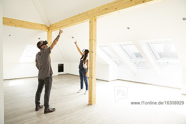 Ehepaar schaut durch Virtual-Reality-Simulatoren  während es auf dem Dachboden seines neuen Hauses steht