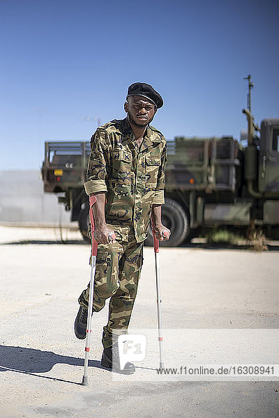 Ein verletzter Soldat steht mit Krücken an einem sonnigen Tag