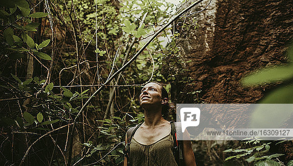 Frau beim Trekking im Wald zwischen Felsen und Bäumen