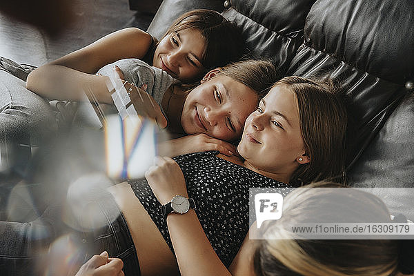 Lächelnde Freunde  die zu Hause auf dem Sofa liegen und kuscheln